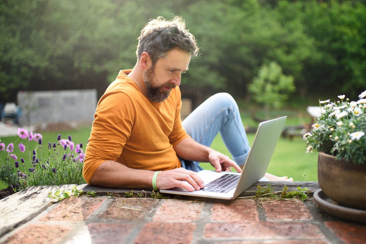 Mann sitzt draußen am Laptop