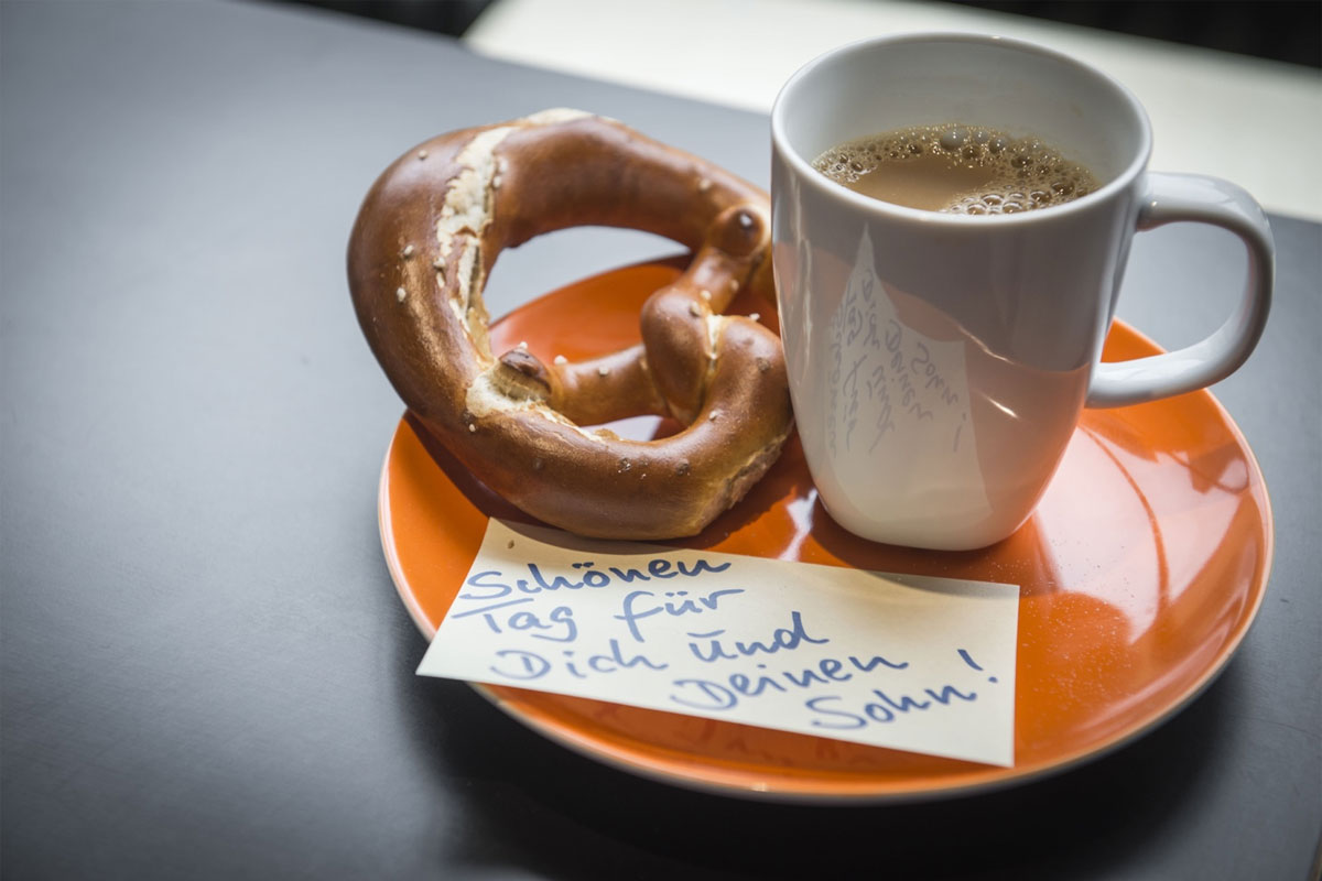Kaffee und Brezel auf Tisch mit beiliegendem Grußzettel
