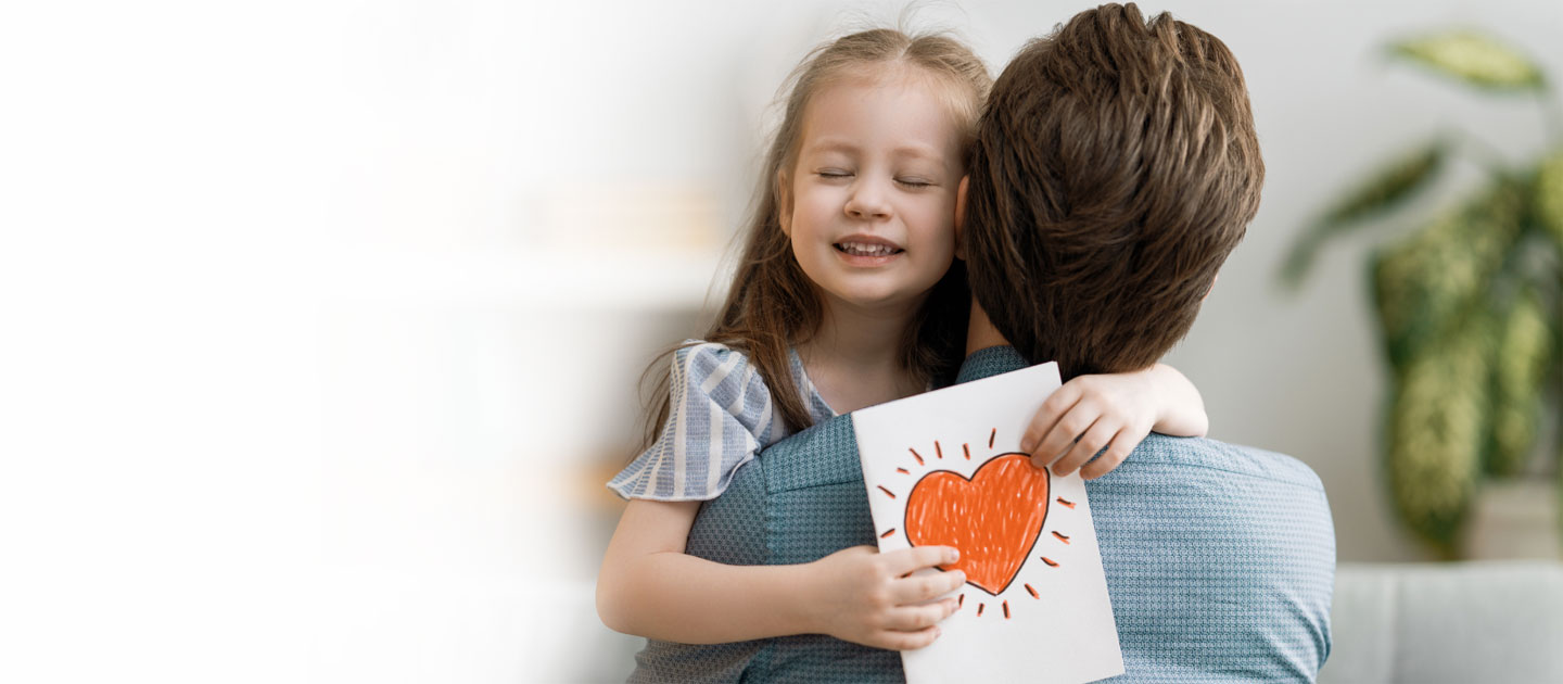 Kind umarmt Vater mit gemaltem Herz in den Händen