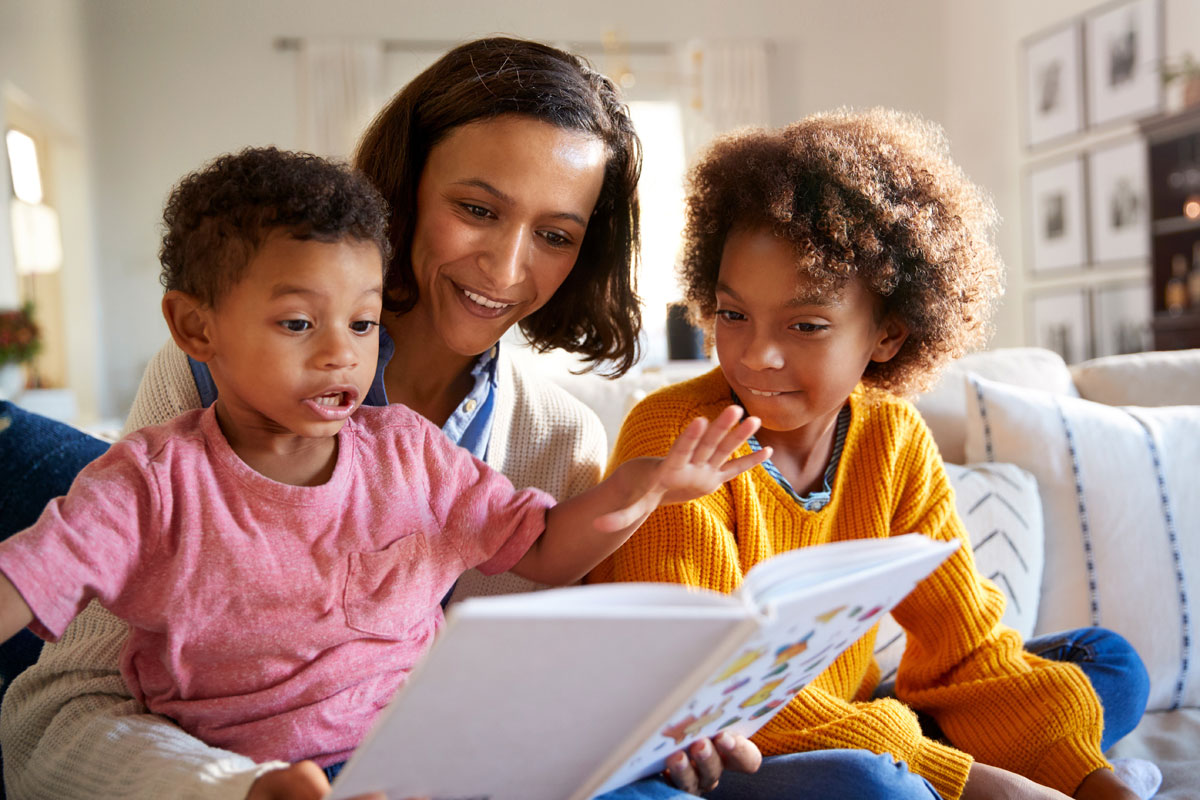 Eine Mutter liest mit ihren beiden Söhnen in einem Buch